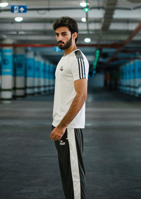 Man standing in a parking garage wearing a white Adidas tracksuit.